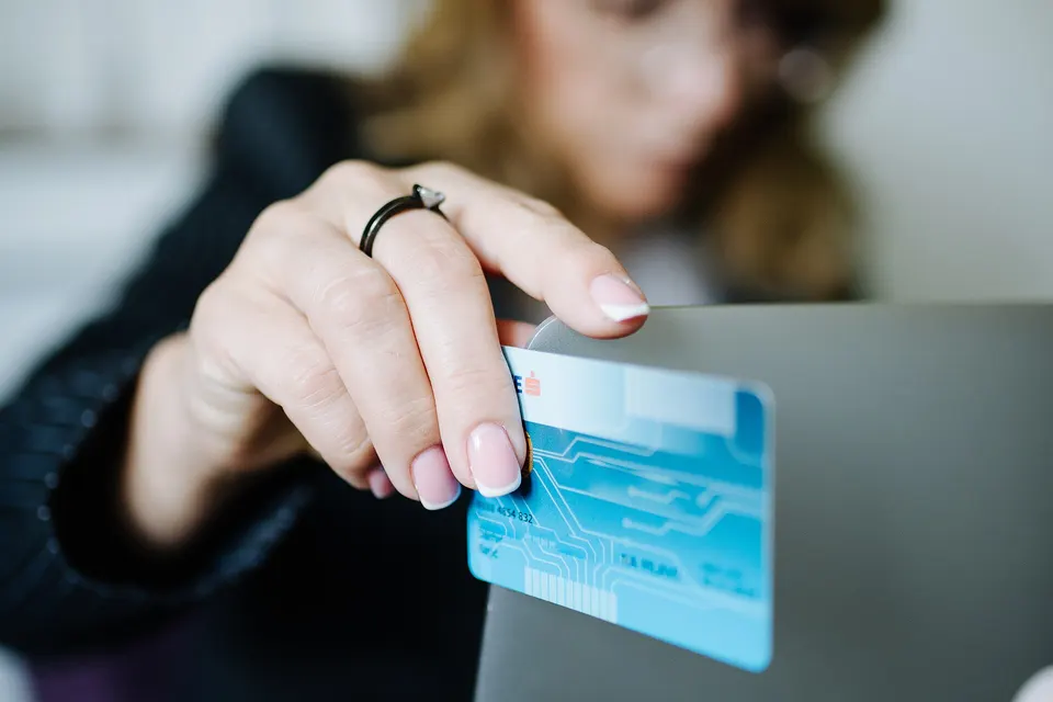 A person holding a credit card while using a laptop at home to make an online purchase